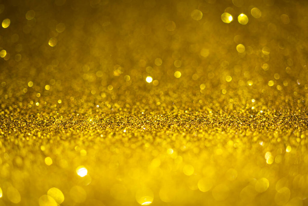 Gold glitter lights. Shiny sparkles, bokeh effects, glowing surface. Selective focus, christmas abstract background photo - Foto, afbeelding