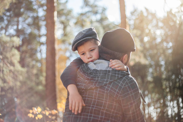 Father`s day. Sad son hugging dad on the  forest background  with copy space. Concept of father-son relationship - Photo, Image