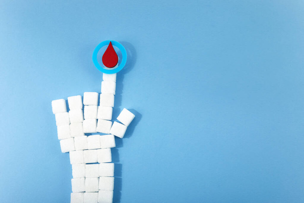 World diabetes day awareness. Blue circle with blood drop and hand shaped sugar cubes. - Fotoğraf, Görsel