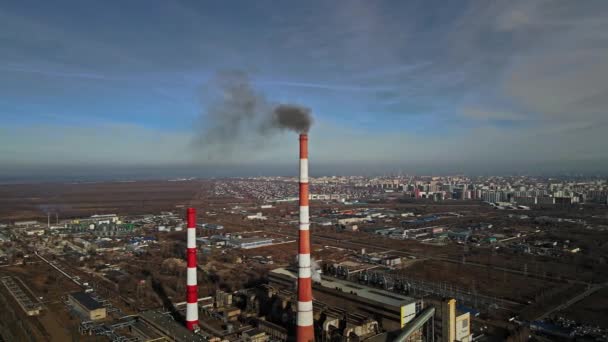 Vista de la ciudad desde arriba sobre el fondo de las tuberías de la central térmica desde la que hay humo. - Metraje, vídeo
