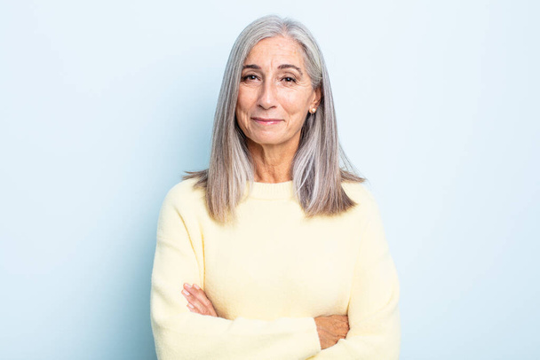 middle age gray hair woman smiling to camera with crossed arms and a happy, confident, satisfied expression, lateral view - Photo, image
