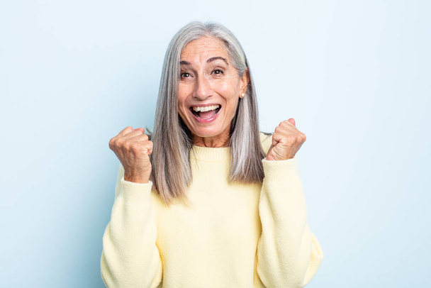 middle age gray hair woman feeling shocked, excited and happy, laughing and celebrating success, saying wow! - Foto, Imagen