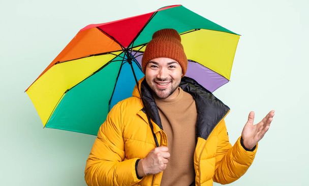young handsome man feeling happy, surprised realizing a solution or idea. rain and umbrella concept - Foto, Bild