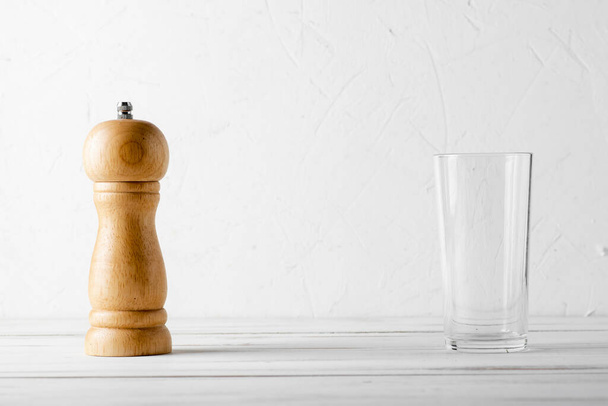 Fa paprika shaker, fűszer chopper és üres üveg csésze fehér fa háttér. Minimális konyhai tervezési koncepció. - Fotó, kép