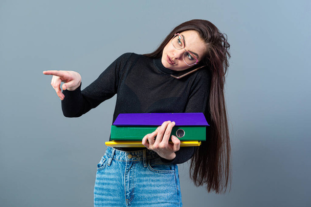 woman with smartphone holding a colorfuls folders with documents, isolated on dark background - Fotografie, Obrázek