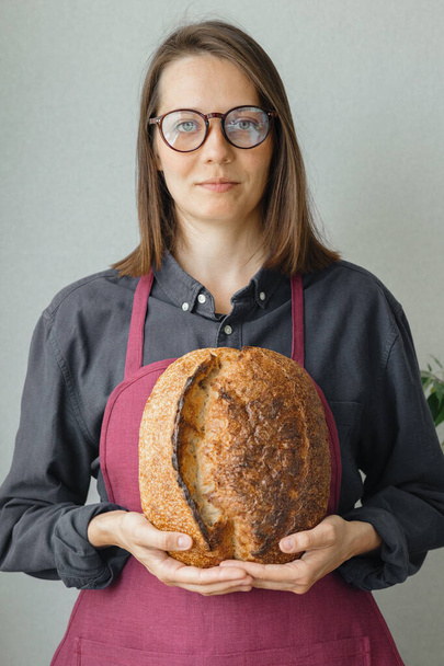 yeast-free sourdough bread. a beautiful European woman baker holds bread in her hands - Foto, Imagem