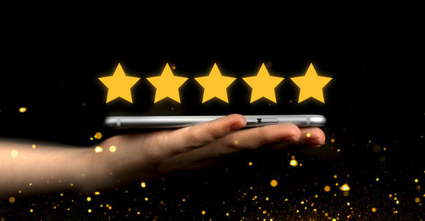 Customer review. Satisfaction, feedback survey background. User give rating, online appliaction or website. Hand with mobile phone, modern smartphone with golden star icon - Photo, Image