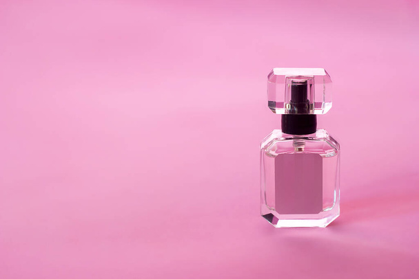 Transparent bottle of perfume eau de toilette on a pink background, perfumery and aromatherapy, copy space for text - Photo, Image