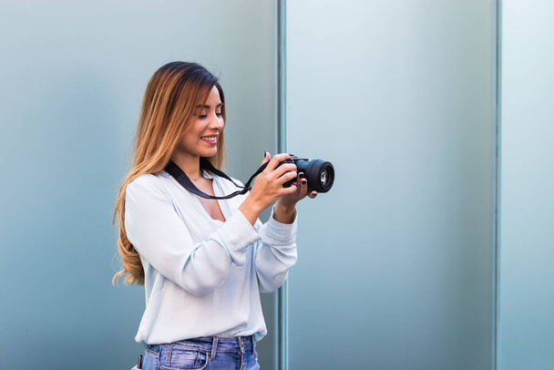 Portrait of beautiful brunette woman smiling while taking photo with professional camera. Hobby concept, background with copy space for text - Photo, Image