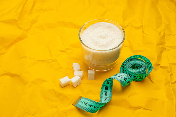 Different types of sugar and diet measuring tape on yellow background with copy space. Diet and healthy food concept. Weight control diet - Fotoğraf, Görsel