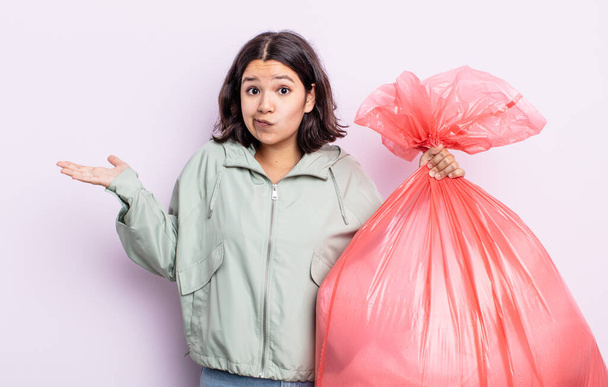 pretty young woman feeling puzzled and confused and doubting. trash bag concept - 写真・画像