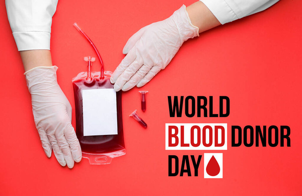 Hands of doctor with blood pack for transfusion on red background. World Blood Donor Day - Photo, Image
