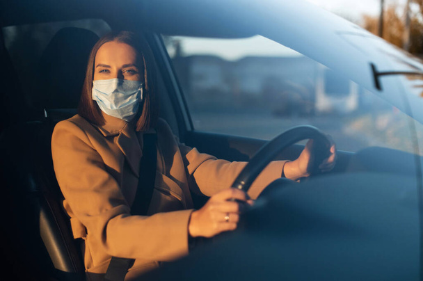 Young woman in smart casual in protective medical mask driving a car - Fotografie, Obrázek