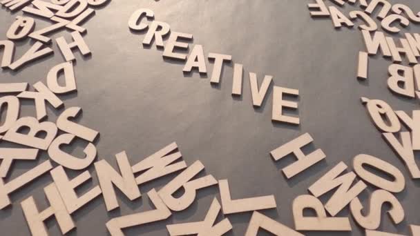 Palabra creativa en letras del alfabeto del cubo de madera Vista superior sobre un fondo de papel rústico. - Imágenes, Vídeo