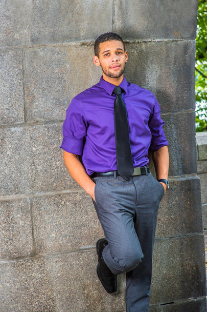 Одягаючись у фіолетову сорочку, сірі штани та чорну краватку, дві руки кладуть у кишені, молодий студент коледжу з маленькою бородою та вусами спирається на стіну, думаючи надворі
 - Фото, зображення