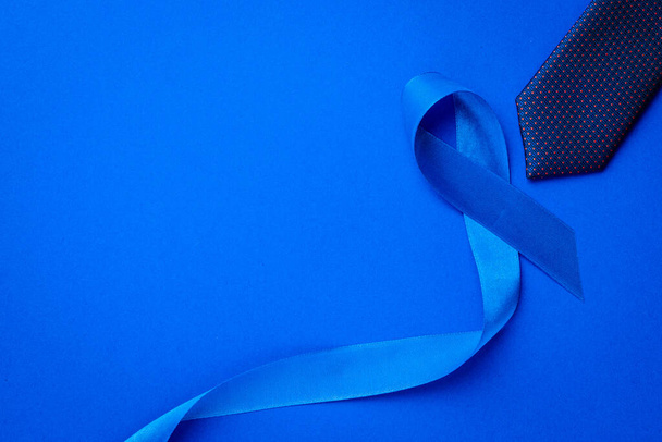 Hombres cancerosos. Concienciación sobre el cáncer de próstata de los hombres salud en noviembre. Cinta azul, corbata de moda aislada sobre fondo azul profundo. Apoyar a las personas que viven y enferman - Foto, Imagen