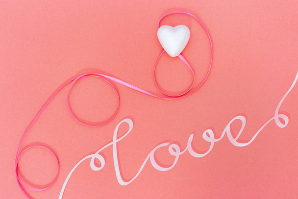 Greeting card with heart and pink ribbon and word love. Copy space. Pastel color background. - Fotografie, Obrázek
