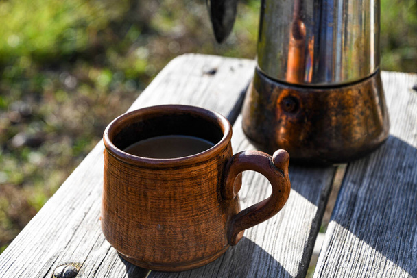  Keramische Tasse mit Kaffee im Garten, zubereitet in einer Geysir-Kaffeemaschine. - Foto, Bild