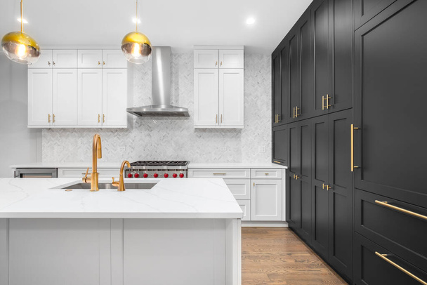 シカゴ,アメリカ- 2019年12月29日:白と黒のキャビネット、金のハードウェア/蛇口、白いハーリンボーン大理石のタイルを備えた豪華な現代的なキッチン. - 写真・画像