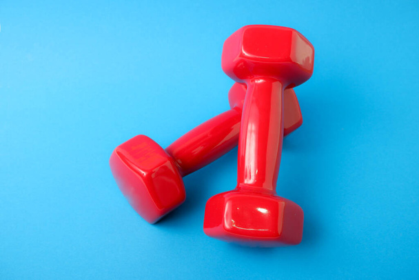 Dumbbells in a plastic sheath on a blue background. Training workout equipment. Sport and exercises. - Φωτογραφία, εικόνα