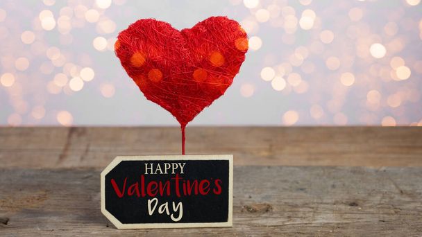 Поздравительная открытка на день святого Валентина - Сердце из красного шара и табличка на деревенской деревянной текстуре стола с романтическими боке огнями - Фото, изображение