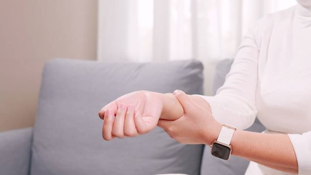 Detail of female hands performing self-massage on the wrist due to damage and pain caused by repetitive movements and excessive use of technology. - Foto, afbeelding