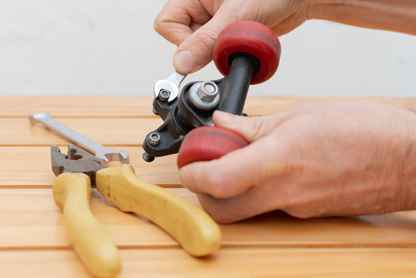 Mãos ajustando porcas com chave e ferramentas na mesa - Foto, Imagem