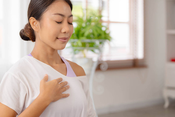 Controle sua respiração apertando o peito. Mulher asiática está realizando ioga, sentado confortavelmente, completando as posturas do banheiro e meditando. - Foto, Imagem