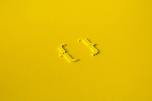 Žlutý dřevěný symbol "závorka" na žlutém pozadí a kopírovat prostor pro sociální média vzdělávací koncept - Fotografie, Obrázek