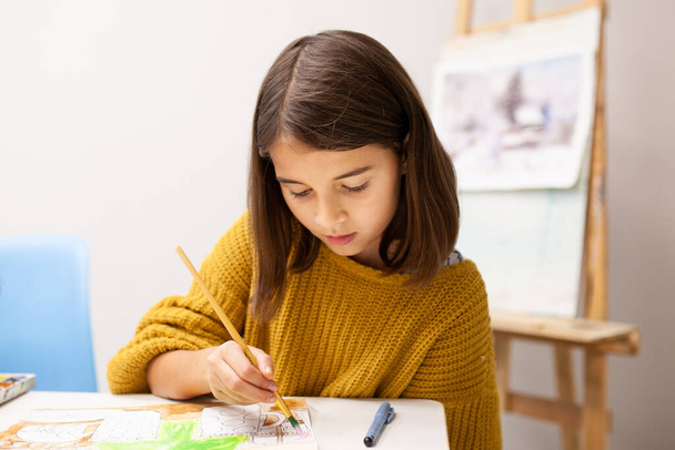 The girl paints with watercolors at the Christmas master class. Education and creativity of children at school. Young artist draws a sketch - Fotoğraf, Görsel