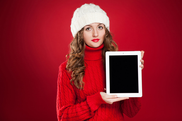 brunette girl wearing red sweater and holding tablet - Foto, afbeelding