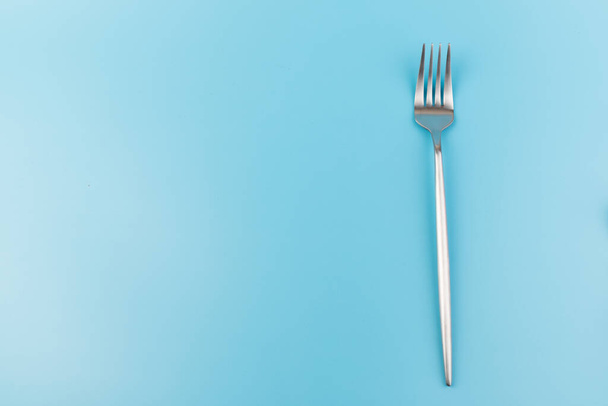 Tenedor de acero sobre fondo azul. Concepto de comedor y utensilios de cocina - Foto, Imagen