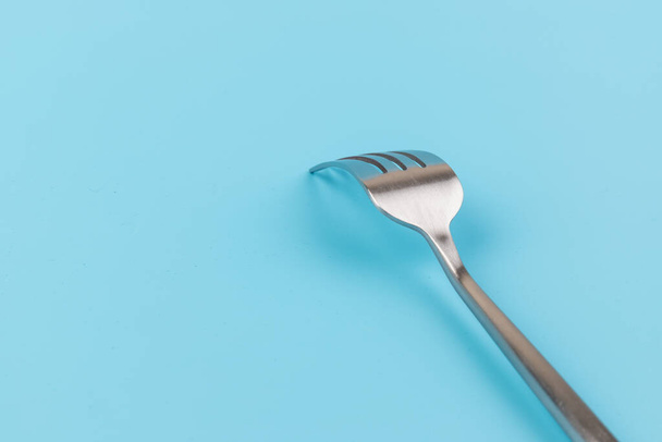 Tenedor de acero sobre fondo azul. Concepto de comedor y utensilios de cocina - Foto, Imagen