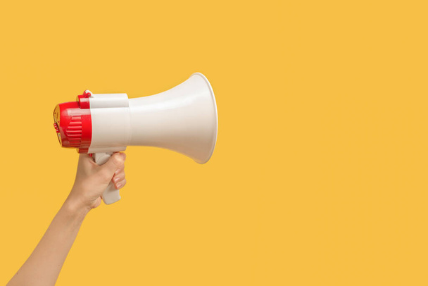 Megaphone in woman hands on a yellow background.  Copy space.  - 写真・画像