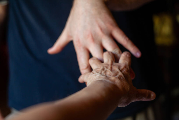An elderly Caucasian hand holding young man hand - Foto, Imagen