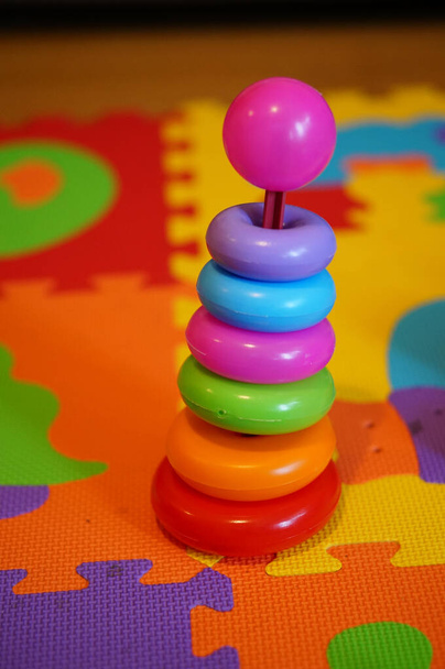 A colorful pyramid kid's toy on the multi-colored mat - Photo, image