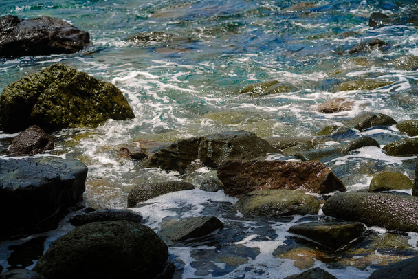 A closeup shot of beach stones and waves - Fotó, kép