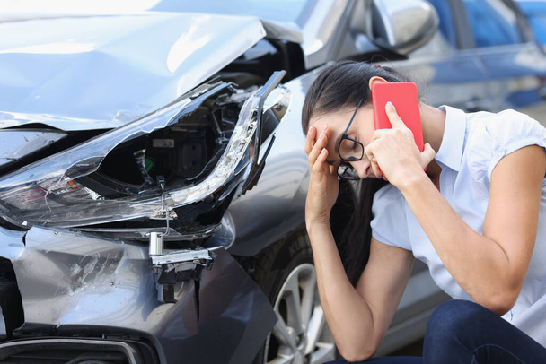 Mujer triste hablando en el teléfono celular cerca de coche destrozado - Foto, Imagen