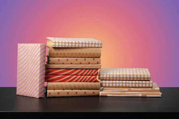 Education concept with stack of books on a table against colored background. - Foto, Imagen