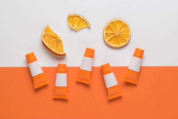 Stukken gedroogde sinaasappels en oranje buizen op een witte en oranje achtergrond. Creatief imago. - Foto, afbeelding