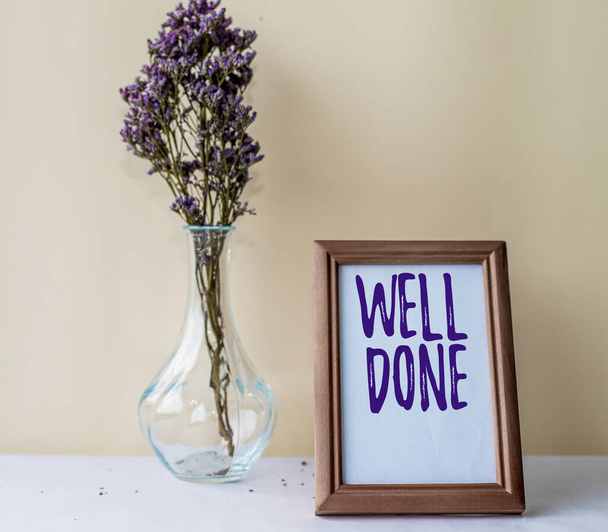 Writing displaying text Well Done. Internet Concept used praising person or group for something have done good way Empty Picture Frame With Flower Vase Standing Top Of Desk. - Foto, Imagem