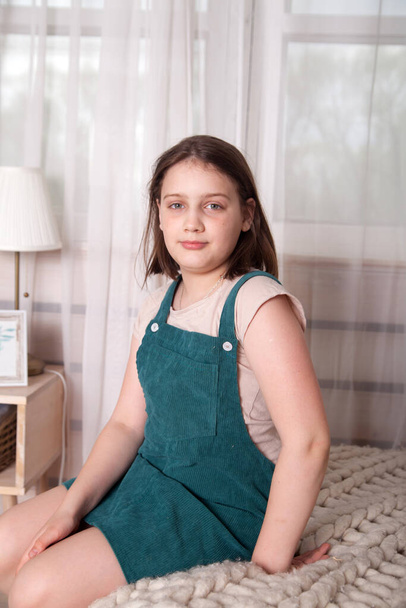 Rus kız. 10 yaşında. Evde, yatakta oturuyor. - Fotoğraf, Görsel