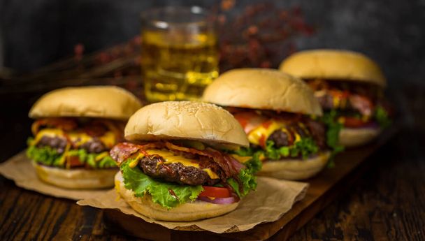 Hamburger di manzo serviti su una tavola di legno con birra in sottofondo soppalco. - Foto, immagini