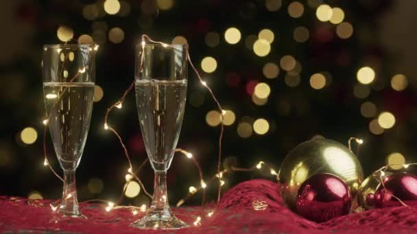 бокалы для шампанского с рождественскими огнями на заднем плане, кадры  - Кадры, видео