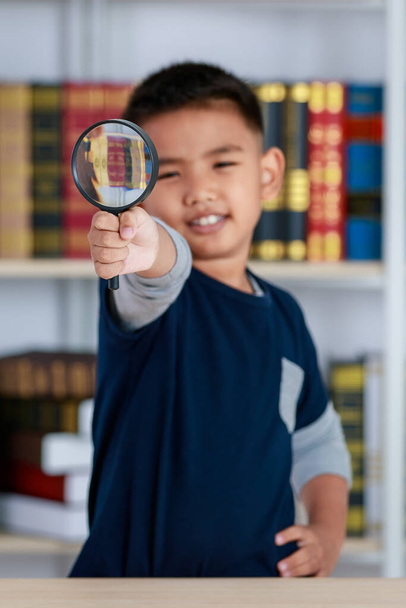 Cercle loupe serrée par le génie garçon asiatique pour étudier les connaissances drôles d'observation scientifique, recherche physique, lumière, lentille, agrandissement d'image dans la bibliothèque de l'école primaire - Photo, image