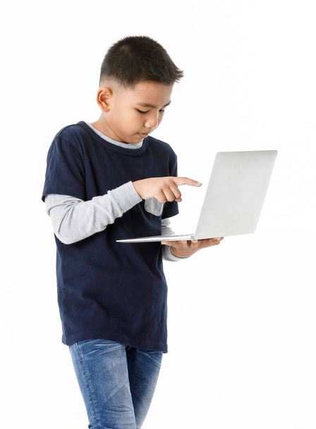 Cutout portrait of smart Asian boy on grey sweater and denim blue shirt wisely standing and concentrate on playing compact laptop he comfortably holding to search for online info of digital technology - Photo, Image