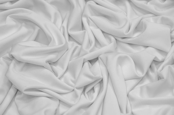 White silk fabric. Texture. Background. Pattern. Dupioni silk fabric has a shiny sheen and characteristic small folds that run horizontally. She lies down in soft folds - Foto, afbeelding