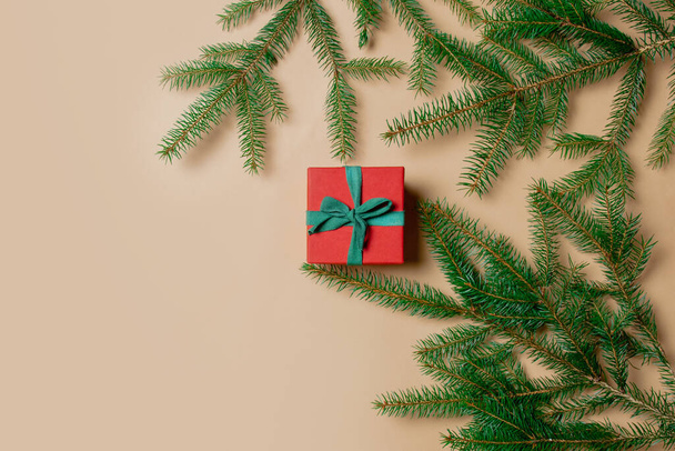 Праздничная подарочная коробка с еловыми ветвями на ярко-белом фоне. Вид сверху  - Фото, изображение