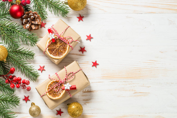 Рождественский фон с елкой, коробка подарков и украшения за белым деревянным столом. - Фото, изображение