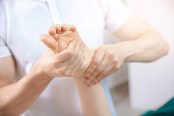 Крупная рука терапевта-остеопата работающего спортивного массажа женской стопой - Фото, изображение